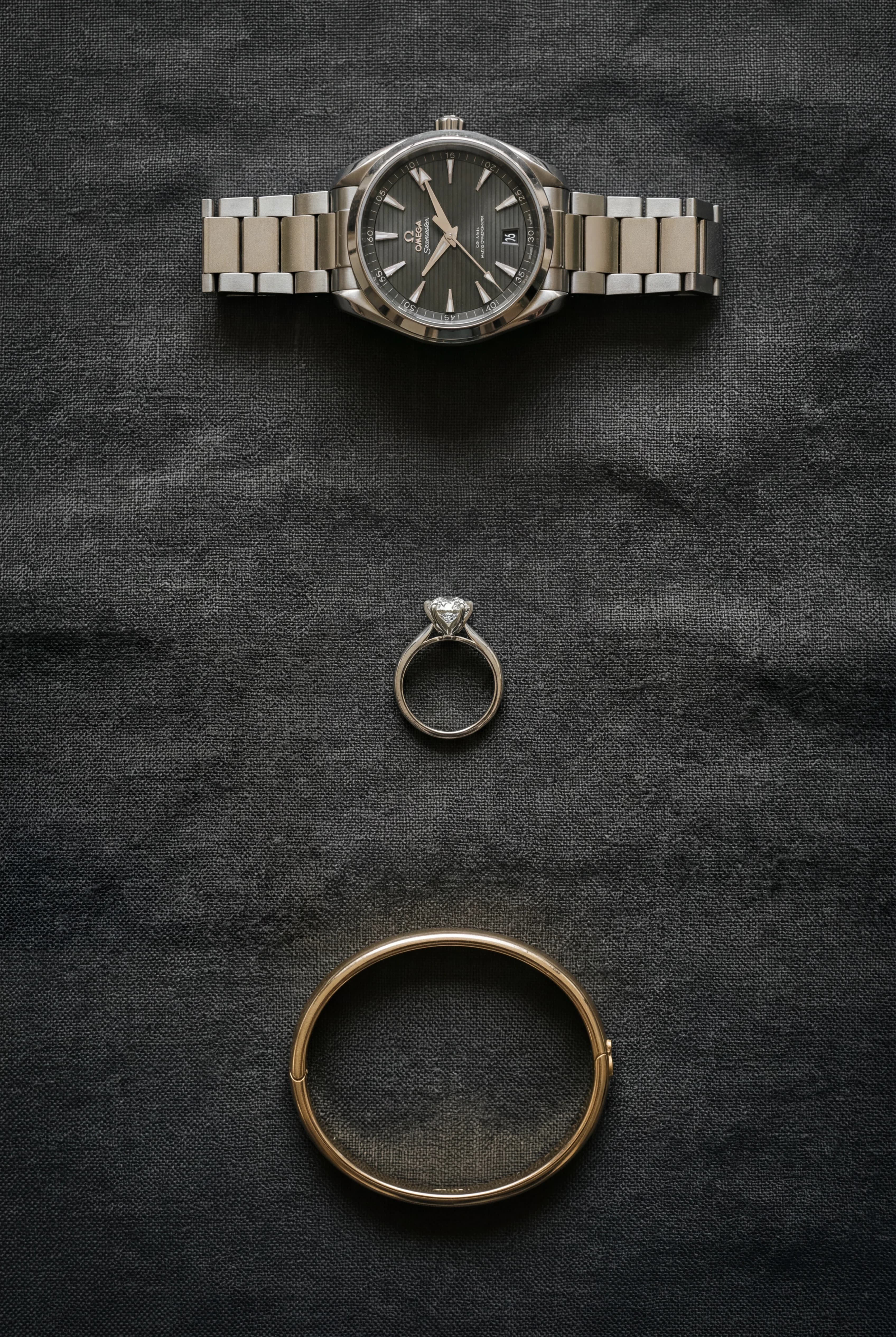 Gold watch, ring and bangle arranged on a flat surface